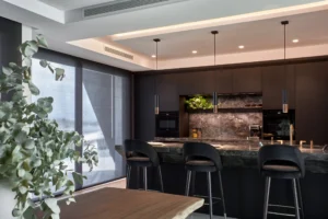 INKO Kitchens premium contemporary kitchen design in Malaga: dark marble island, black cabinets, warm lighting and bar bench.