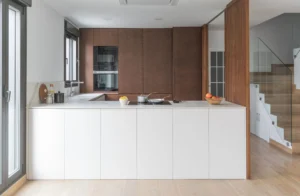 INKO Cocinas cocina de diseño premium con isla blanca, mobiliario en madera oscura y electrodomésticos empotrados.