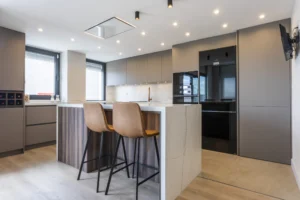 INKO Cocinas cocina moderna de diseño premium con isla de mármol, encimeras blancas, muebles gris acero y taburetes de cuero.