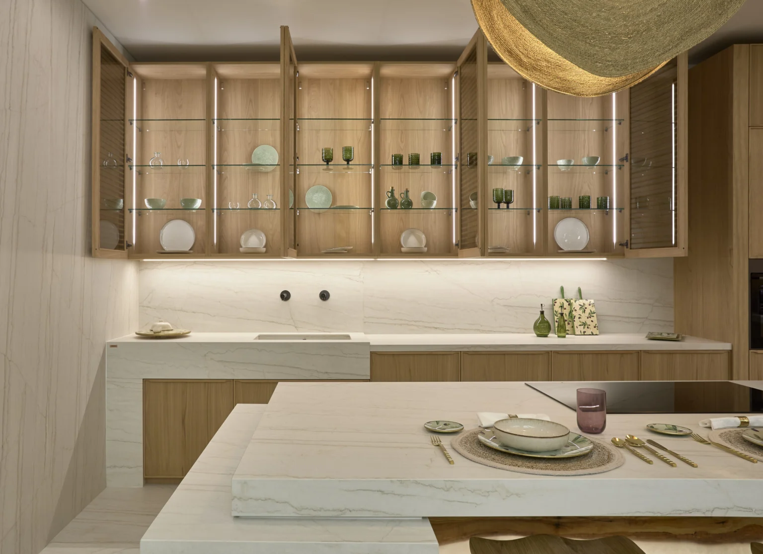 INKO Cocinas: cocina de diseño moderno premium en madera y mármol con vitrinas de vidrio iluminadas, isla central y vajilla verde