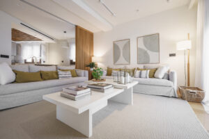Sala de estar amplia y luminosa con dos sofás grises, mesa de centro blanca, planta y arte abstracto; ambiente premium INKO Cocinas
