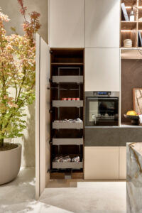 INKO Cocinas cocina moderna con armarios en tonos claros, despensa extraíble de madera y horno empotrado; diseño de cocinas premium.