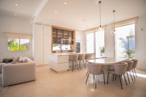 INKO Kitchens - modern kitchen with central island, white premium design furniture, beige stools and great lighting effect.