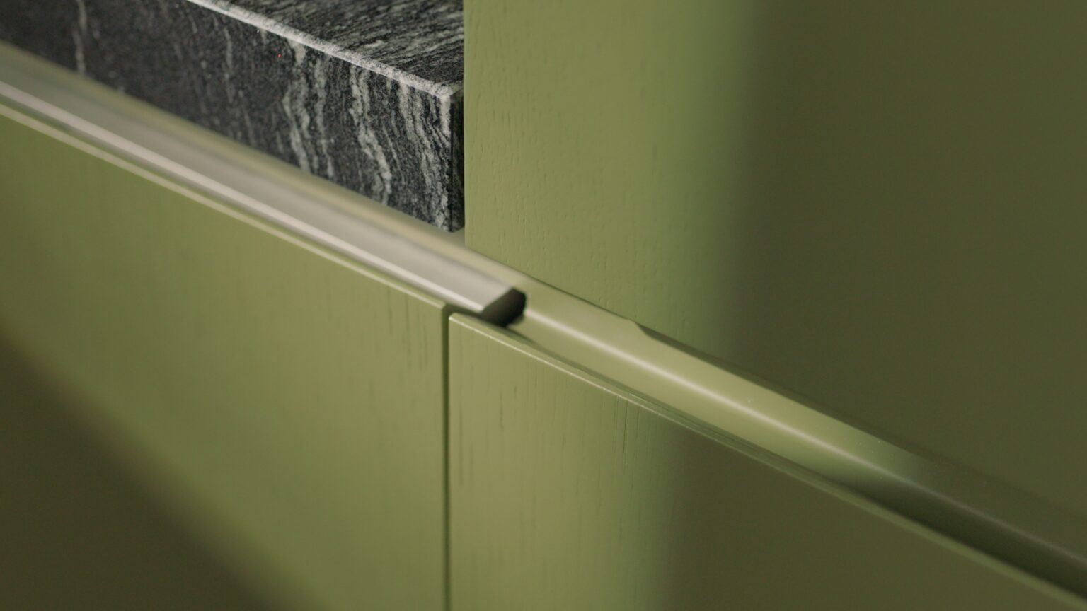 INKO Cocinas puerta de mueble verde oliva con detalle de tirador de perfil metálico y encimado oscuro, diseño de cocinas premium en Málaga