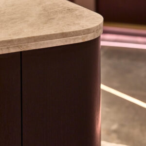 Elegante isla curva con encimera de mármol pulido y mueble de madera oscura, diseño y calidad premium — INKO Cocinas