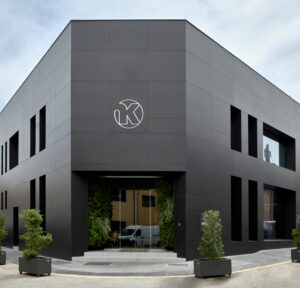 Fachada minimalista y elegante de showroom negro con entrada acristalada y jardín vertical, diseño premium a medida. INKO Cocinas