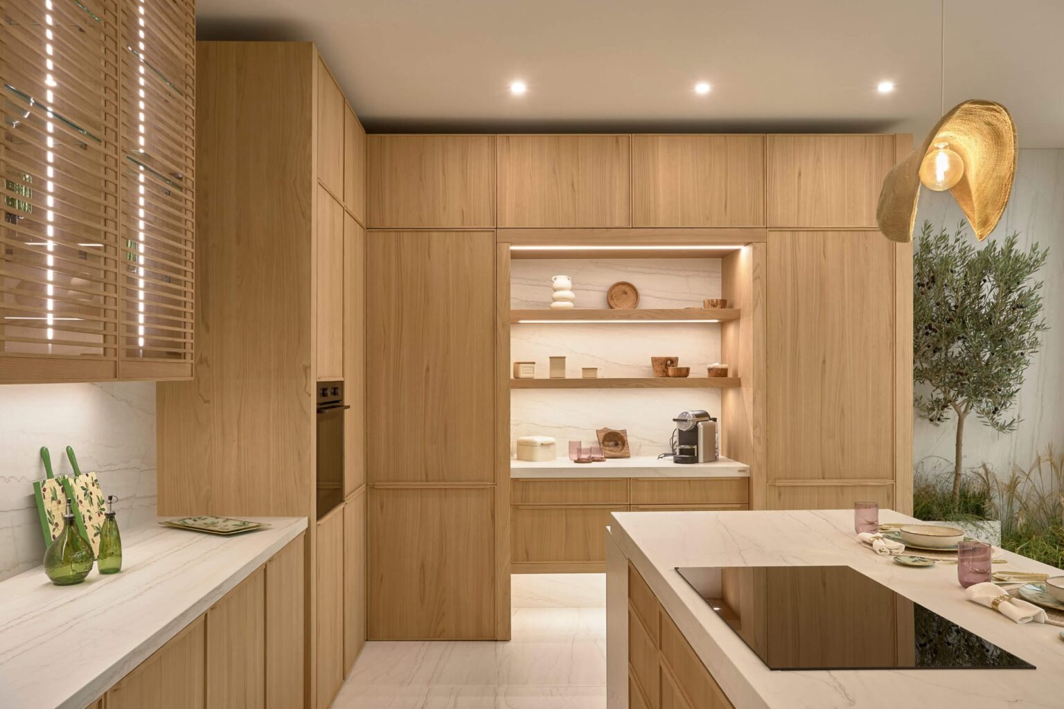 Cocina de diseño en madera natural con isla y placa de inducción, estanterías empotradas y encimeras de mármol, acabado premium — INKO Cocinas