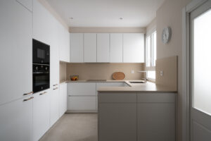 Cocina moderna minimalista en tonos neutros con encimera de piedra y acabados en lacado mate – INKO Cocinas, fabricantes en Málaga.