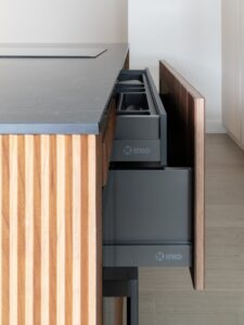 Cocina moderna a medida con isla de piedra y acabados en madera natural, destacando la elegancia y funcionalidad – INKO Cocinas, fabricantes en Málaga.