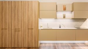 Cocina moderna con acabados en madera y lacado beige, encimera de piedra y detalles de iluminación cálida – INKO Cocinas, fabricantes en Málaga.