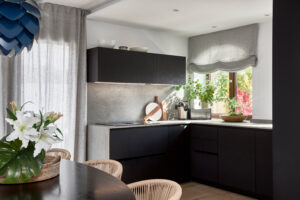 INKO Cocinas - Cocina contemporánea en negro mate, encimera gris y plantas junto a la ventana; diseño y calidad premium.