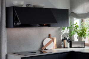 INKO | Fabricantes de Cocinas en Málaga y Diseño a Medida | INKO | Fabricantes de Cocinas en Málaga y Diseño a Medida | INKO Cocinas cocina contemporánea con armarios negros de diseño premium, placa de inducción y planta junto a la ventana.