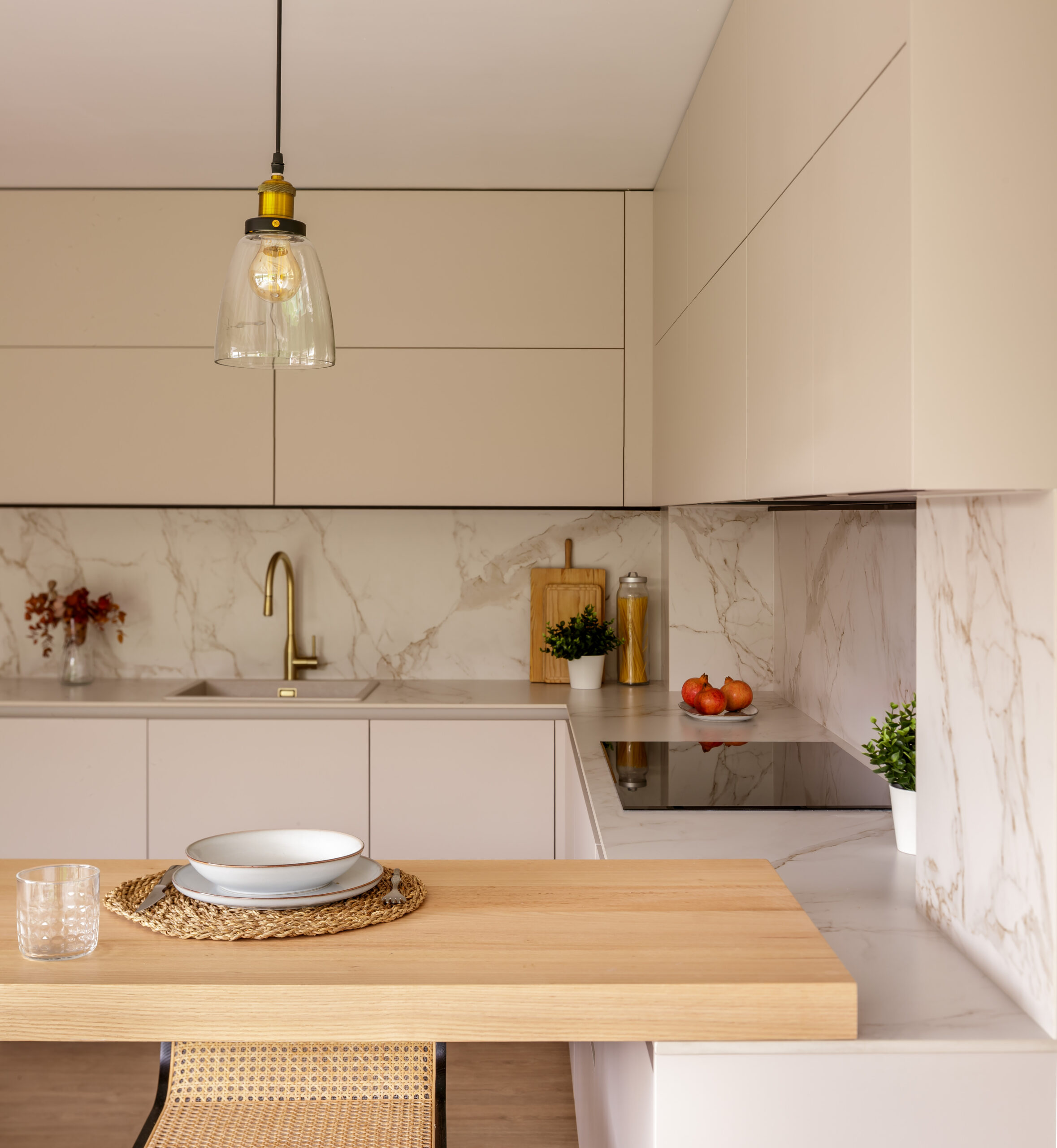 Cocina moderna en lacado crema con frente y encimera en mármol, península de madera natural, grifo dorado e iluminación cálida – INKO Cocinas