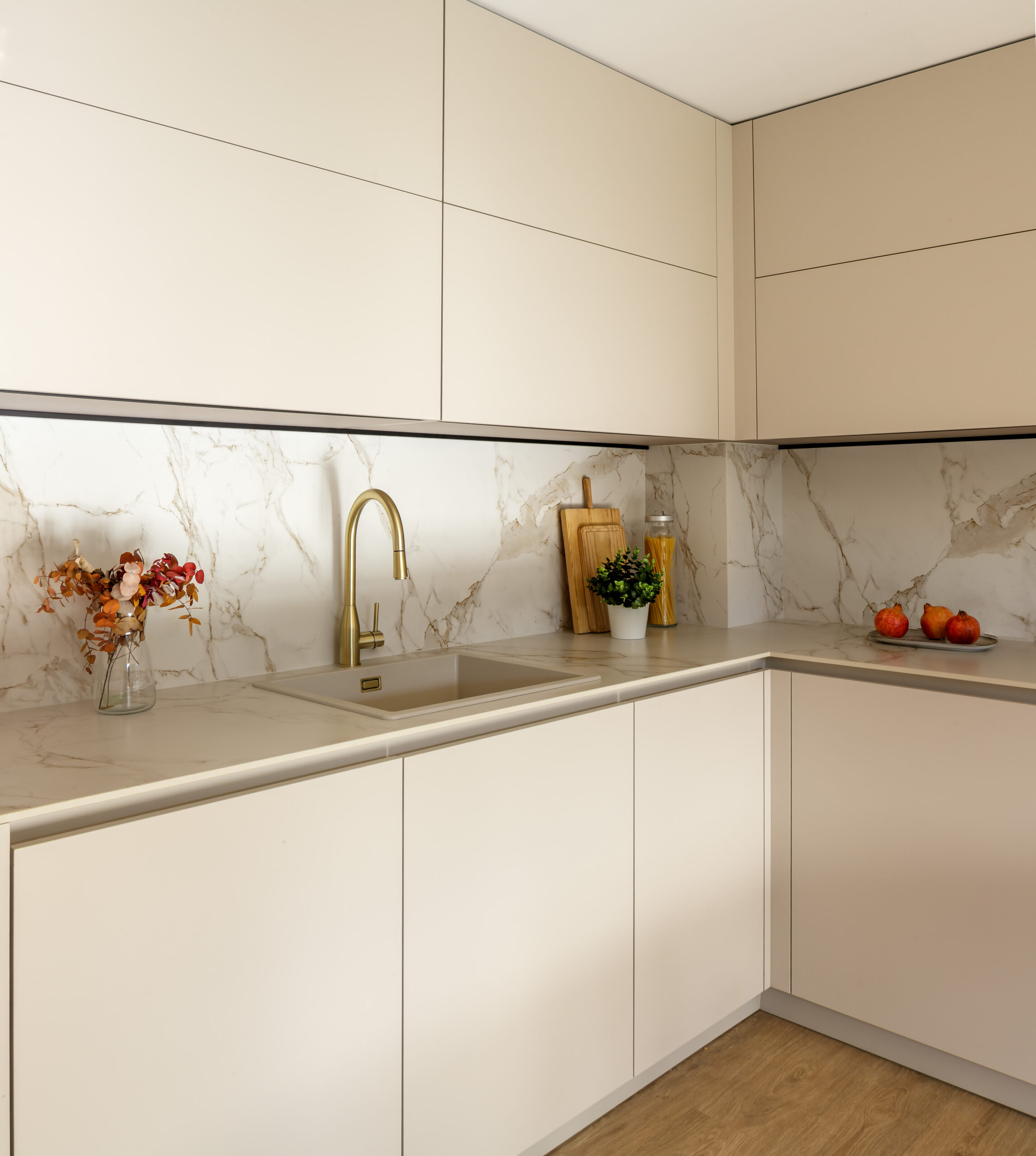 Cocina moderna en lacado beige mate con encimera y salpicadero en mármol, grifo dorado, suelo de madera y líneas rectas – INKO Cocinas