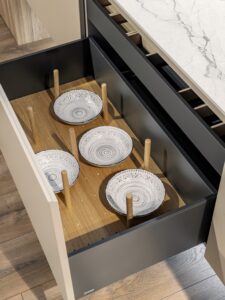 Cocina moderna con cajones elegantes en lacado gris y madera, organizando platos de cerámica – INKO Cocinas, fabricantes en Málaga.