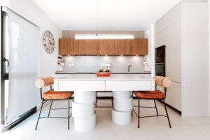 INKO | Fabricantes de Cocinas en Málaga y Diseño a Medida | INKO Cocinas cocina moderna con armarios de madera, encimera blanca, isla central y sillas naranja de diseño premium.