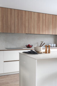INKO | Fabricantes de Cocinas en Málaga y Diseño a Medida | INKO Cocinas cocina de líneas minimalistas con armarios de madera en la pared, encimera blanca y isla central de diseño premium.